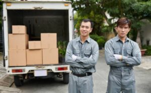 team of professional movers standing in front of moving truck with boxes