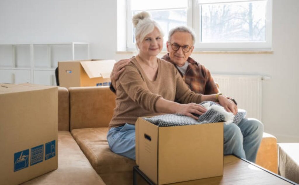 Senior couple stepping up the porch with moving boxes and bright smiles