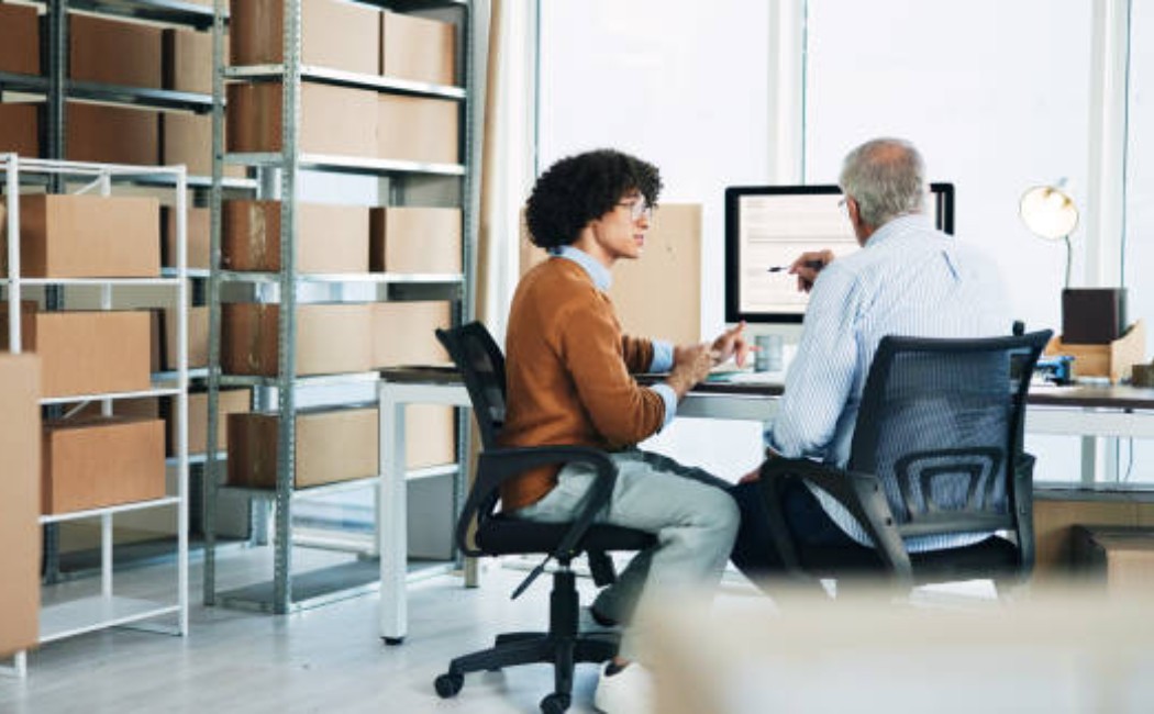 Warehouse staff planning orders witha laptop open