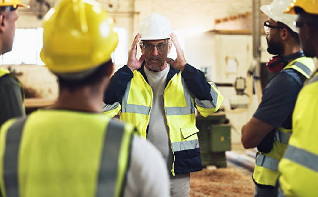 Engineer and team checking building maintenance plans outside.