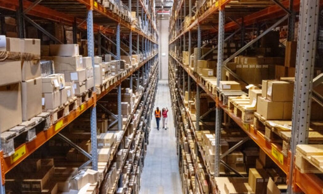 Team of workers walking down an aisle in a modern warehouse.