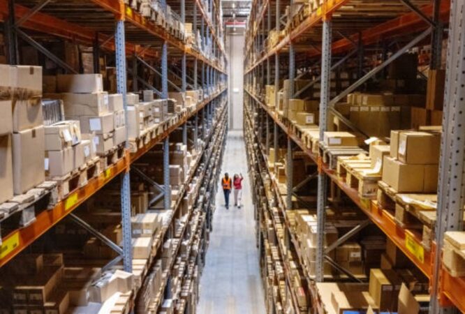 Team of workers walking down an aisle in a modern warehouse.
