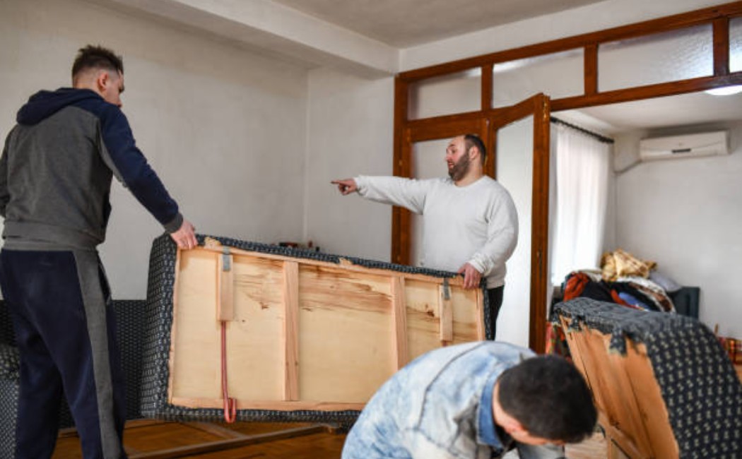 Person gesturing at a couch setup with friends in a casual room.