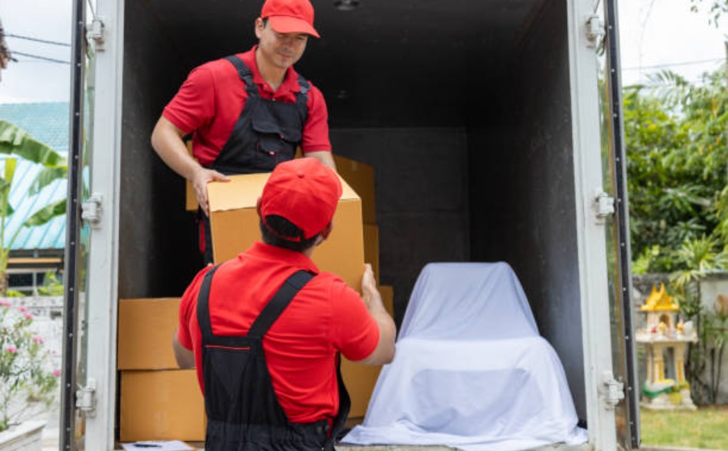 Moving crew unloading household items from a white pickup truck.