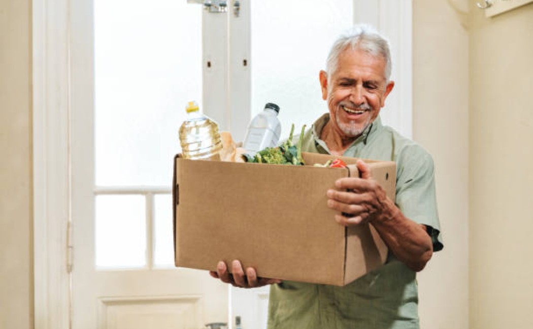 Senior shopper with a box of fresh produce and groceries