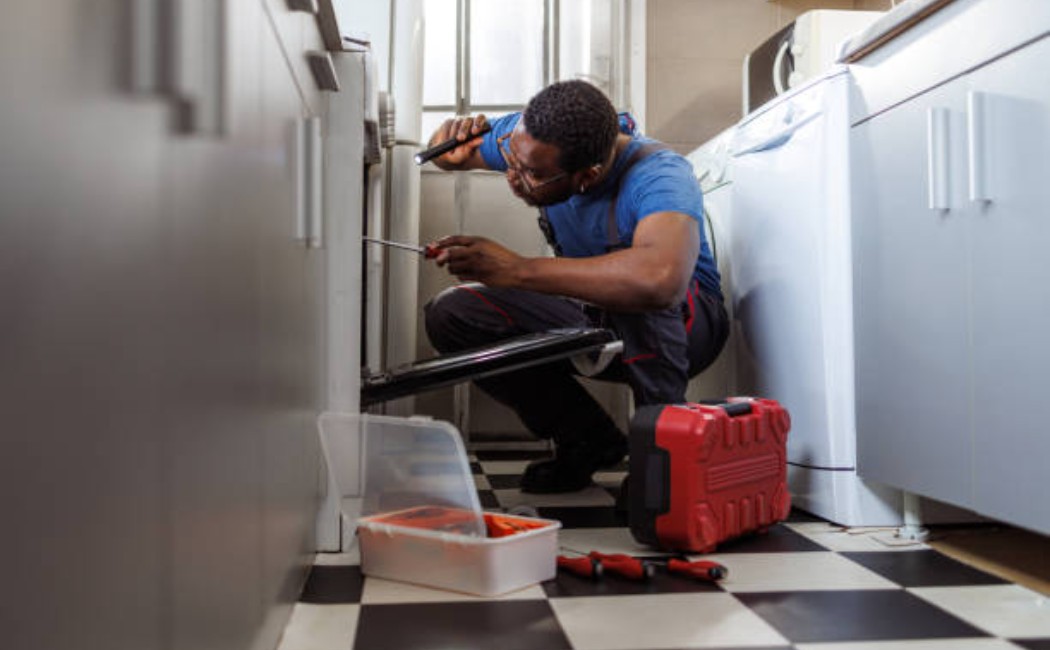 Handyman installing parts on a stove.