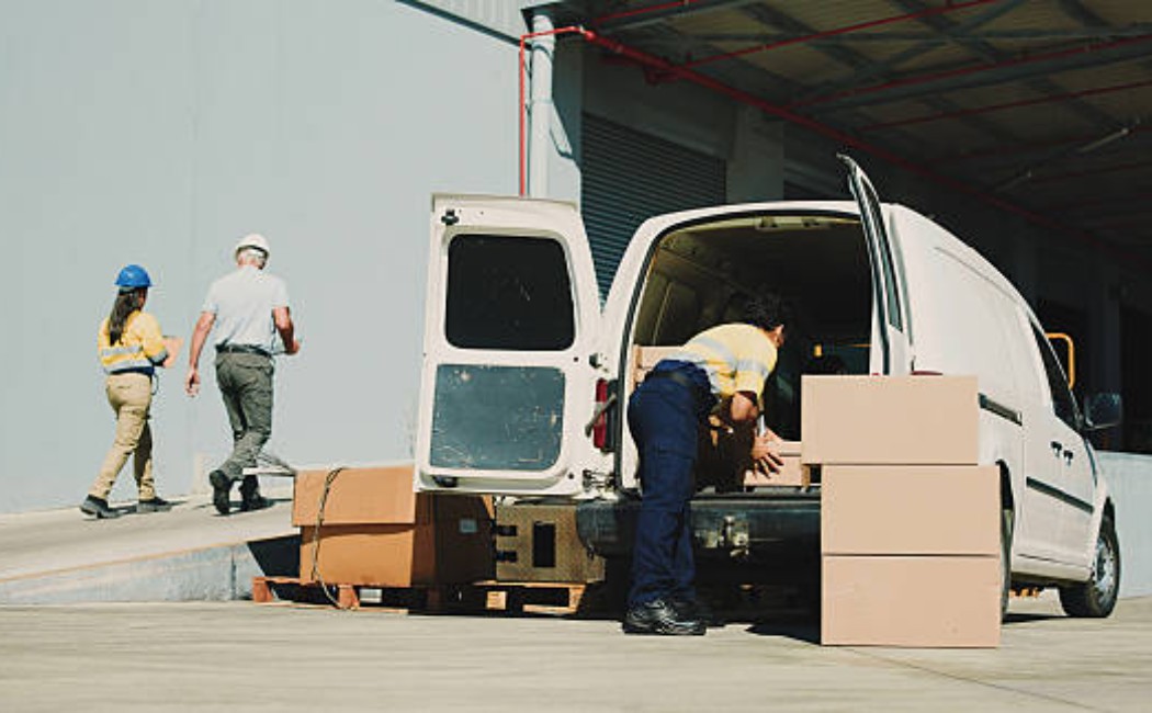 Man loading packages into a delivery van outdoors.